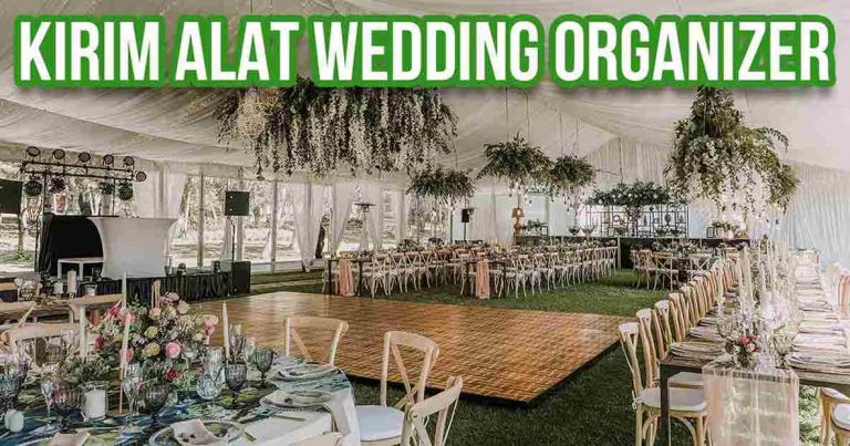 Interior tenda pernikahan besar dengan tulisan 'KIRIM ALAT WEDDING ORGANIZER' di atas, menampilkan meja panjang dan dekorasi bunga gantung, memberikan nuansa elegan dan terorganisir.