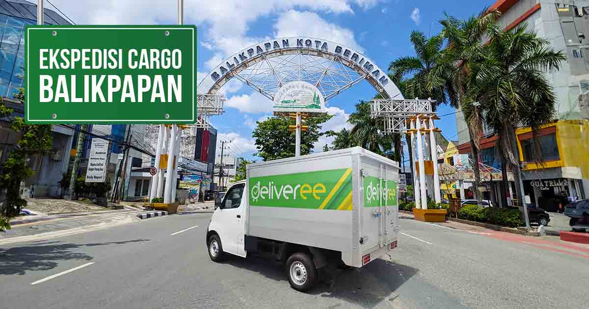 Mobil truk Deliveree putih melaju di jalan Balikpapan, dengan gerbang 'Balikpapan Kota Beriman' dan papan 'Ekspedisi Cargo Balikpapan' di latar belakang.