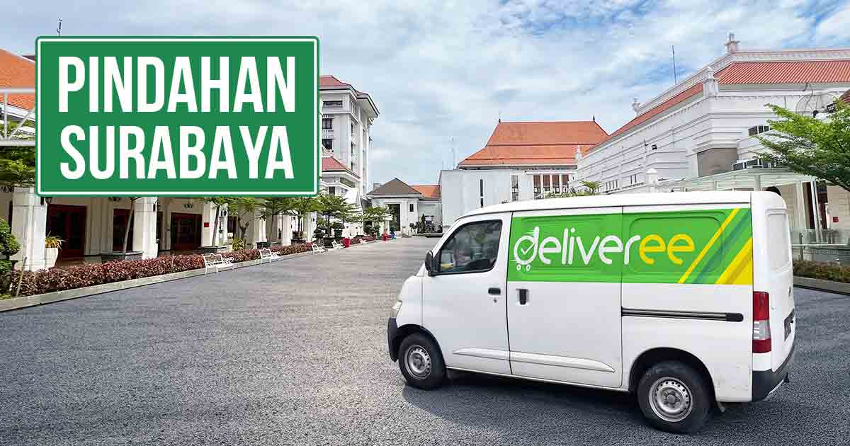 Mobil Deliveree di area pindahan Surabaya dengan latar belakang bangunan dan tulisan 'Pindahan Surabaya'.