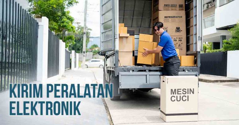 Pria memuat kotak peralatan elektronik ke dalam truk untuk pengiriman, dengan kotak bertuliskan "MESIN CUCI" di bagian depan truk.