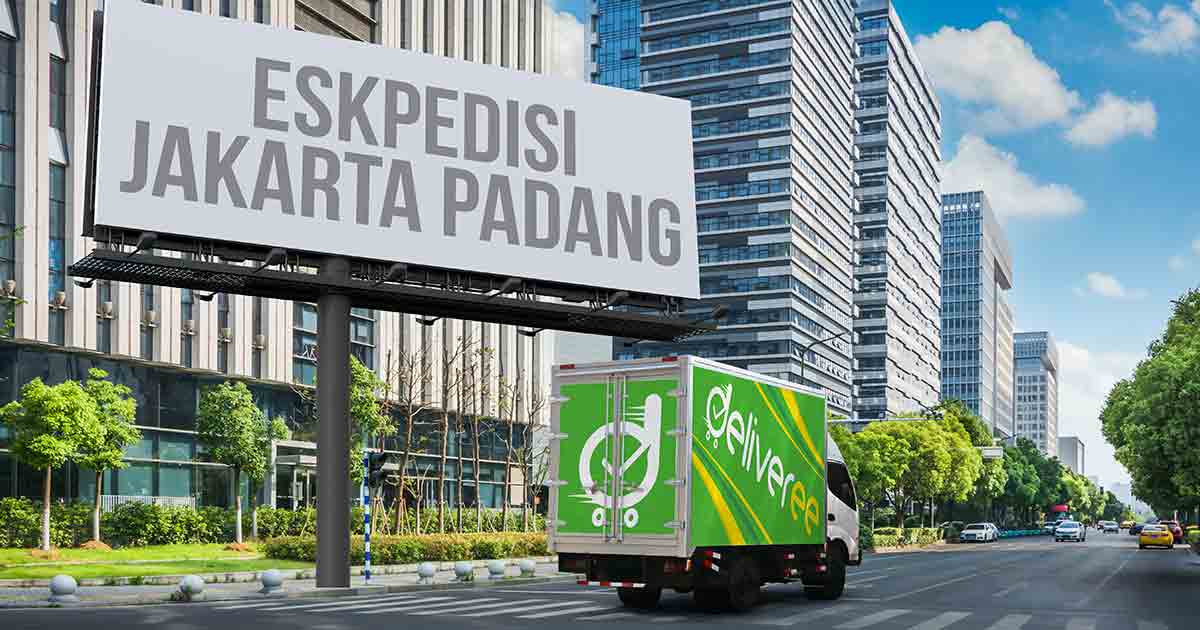 Truk Deliveree melintas di jalan perkotaan dengan papan reklame bertuliskan "Ekspedisi Jakarta Padang."